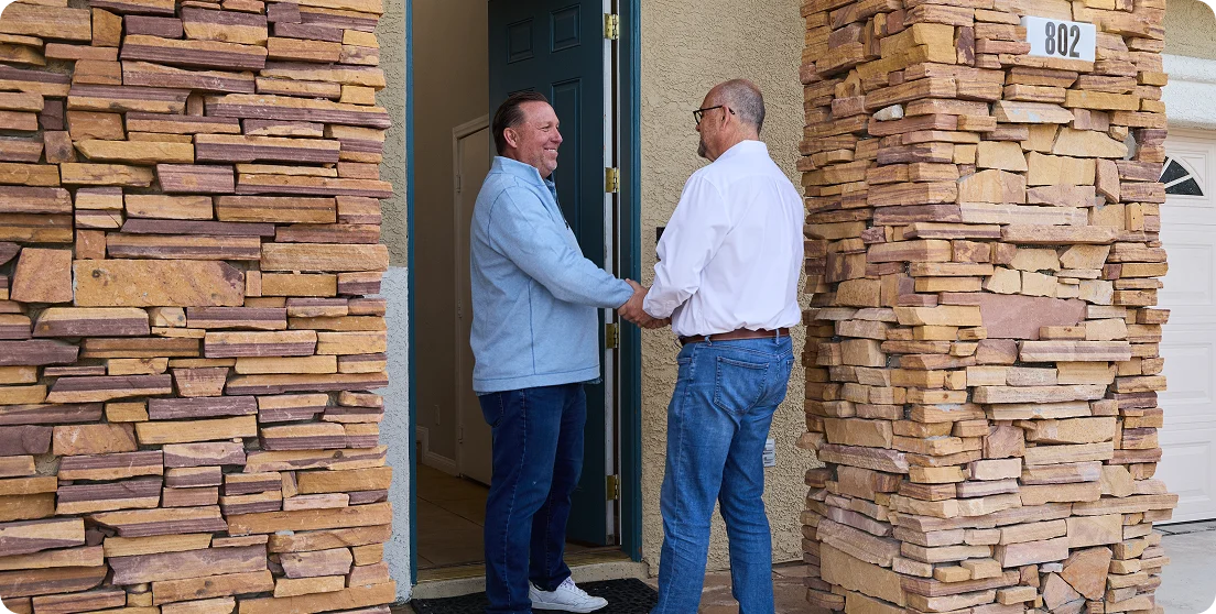 Two men standing in doorway shaking hands